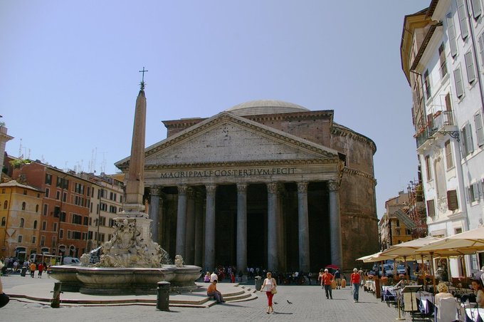 This photo shows an exterior view of the Pantheon as it stands today. The building is circular with a portico of large granite Corinthian columns under a pediment.