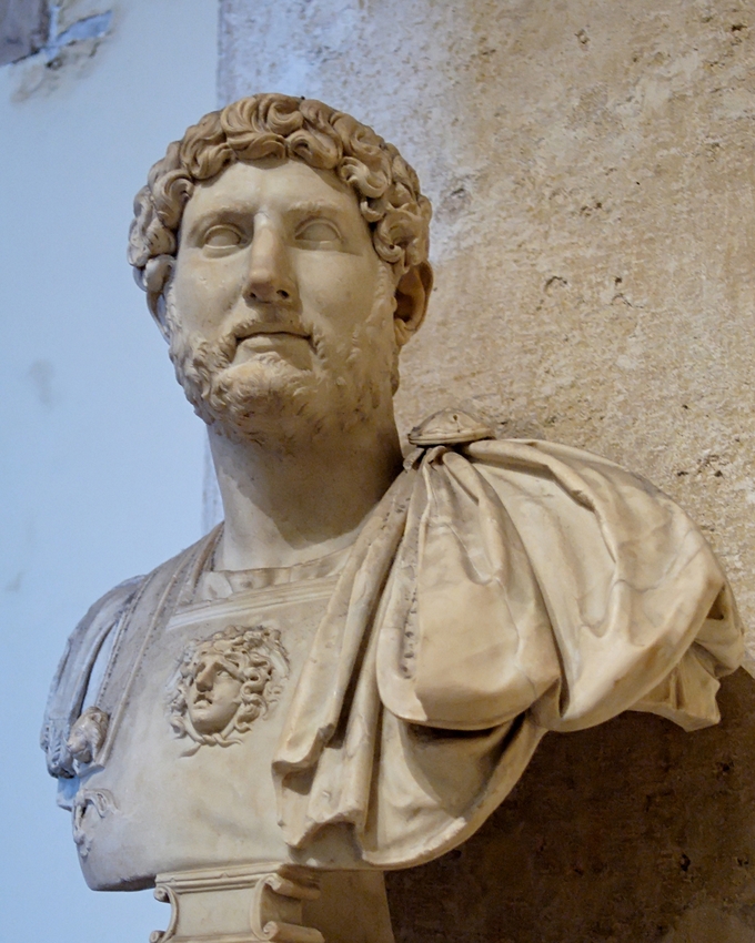 This photo shows a bust of Hadrian. He has curly hair and a beard.