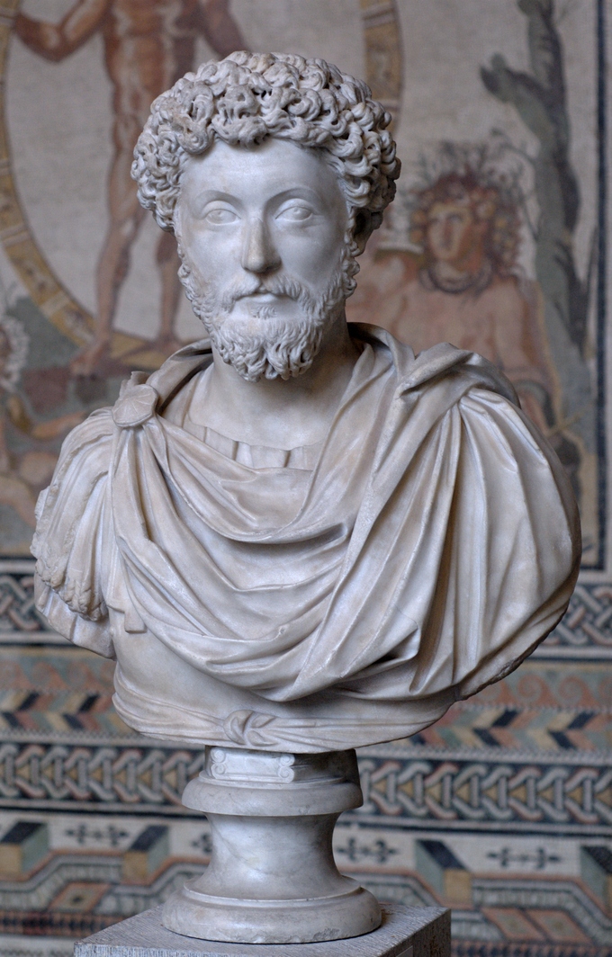 This is a photo of a bust of Marcus Aurelius. He has curly hair and long, curly beard.