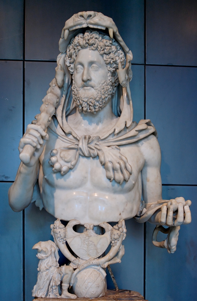 This photo shows a statue of Commodus as Hercules. Here, the Roman Emperor has taken on the guise of the mythological hero, Hercules. He has been given the attributes of the hero: a lion skin placed over his head, a club placed in his right hand, and the golden apples of Hesperides in his left.