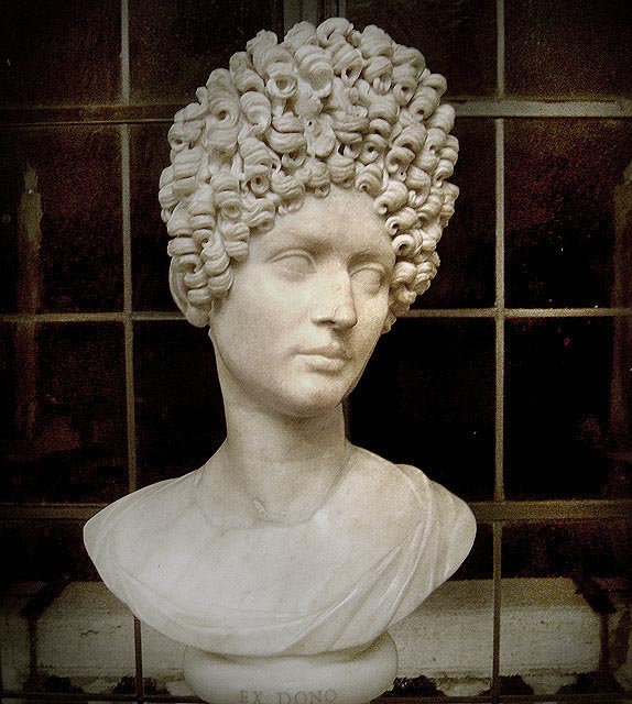 This is photo of a bust of a Flavian woman. It shows a fashionable Flavian hairstyle, a stack a tight curls arranged at the crown.
