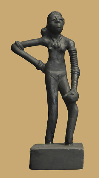 This is a photo of the Dancing Girl of Mohenjo-daro. Full-length statuette of a nude female figure with long, lean legs and stylized facial features. She wears a stack of bracelets and a large necklace.