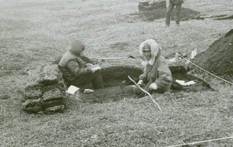 Black and white photo of two people digging in the archaeological site.