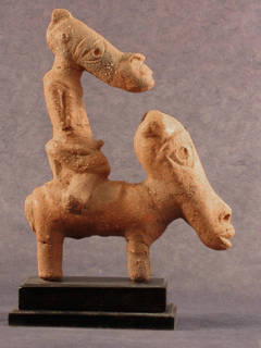 A clay figure of a rider on a horse, both with elongated faces.