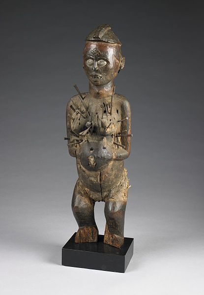 A figurine of a female with nails protruding from her body.