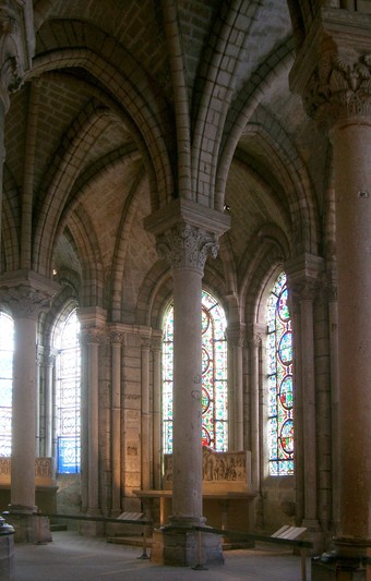 Image of ambulatory shows pillars, stained glass, and light.