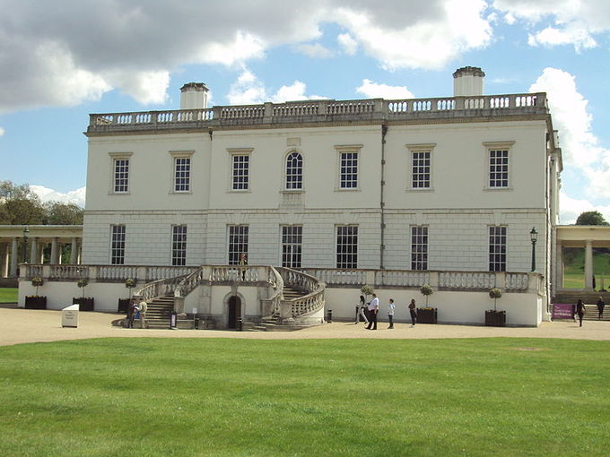 Picture of the Queen's House with a green yard in the foreground. The white house is a simple, symmetrical box design.