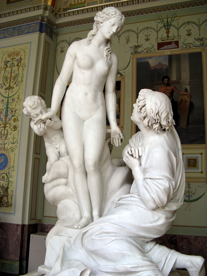 Escultura representa a Pigmalión de rodillas, enamorándose de una escultura de mujer. Un querubín besa la mano de la mujer.