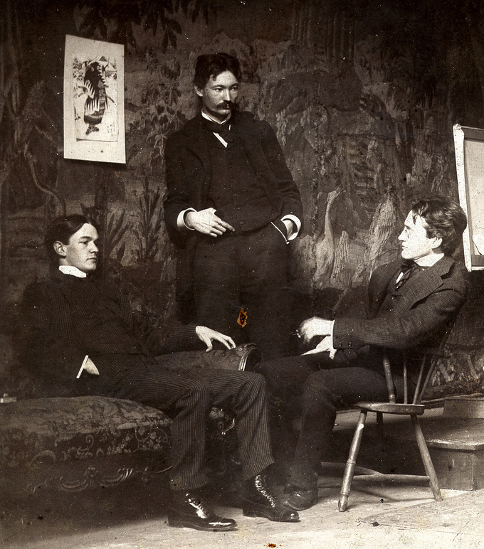 A black and white photo of the three artists at leisure with each other. Shinn and Sloan are seated, and Henri stands between them.