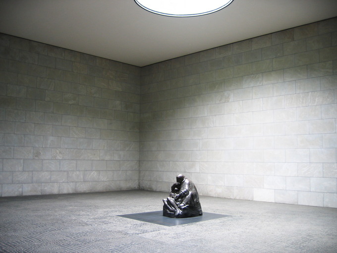 Photo of the sculpture depicting a mother cradling her dead son in a large, empty room.
