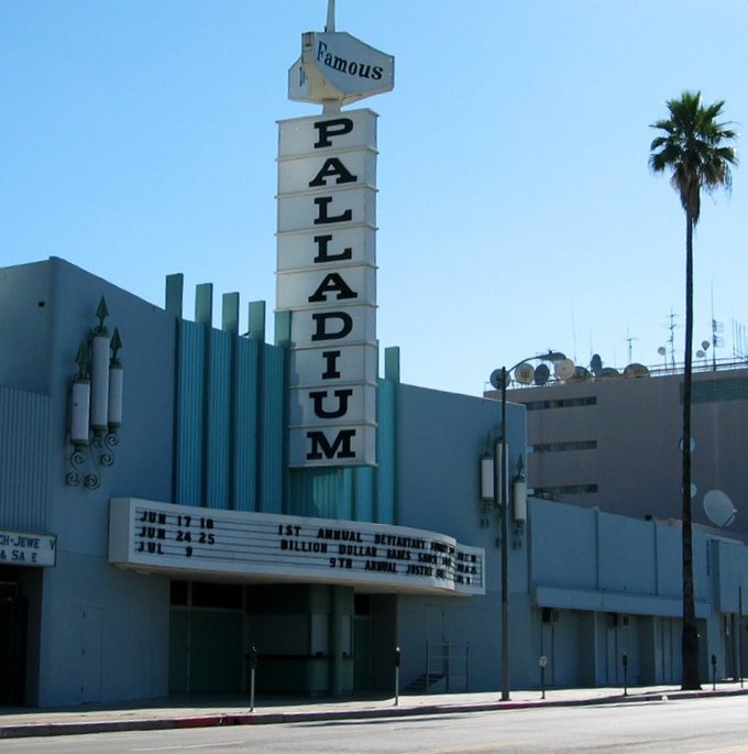 Photo shows the Palladium from outside. Its name is on a huge vertical sign in the center, and film showings are advertised.