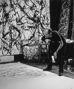 This black and white photo shows Jackson Pollock at work in his studio.