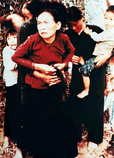 A photograph shows a group of Vietnamese women and children holding one another tightly, with looks of terror on their faces.