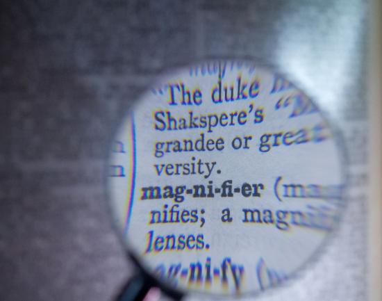 magnifying glass zoomed in on dictionary definitions with a blurred background