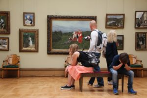 Two teenagers sitting in a museum with their heads in their hands.