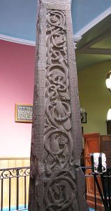 Photo of a stone pillar with bas relief carvings, inside a museum