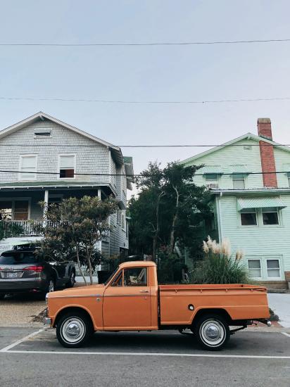an orange pick up truck parked in front of a house