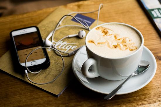 a picture of an iphone, headphones and a coffee