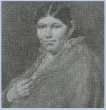 Fuzzy black/white portrait of a Cherokee woman sitting, wrapped in a blanket