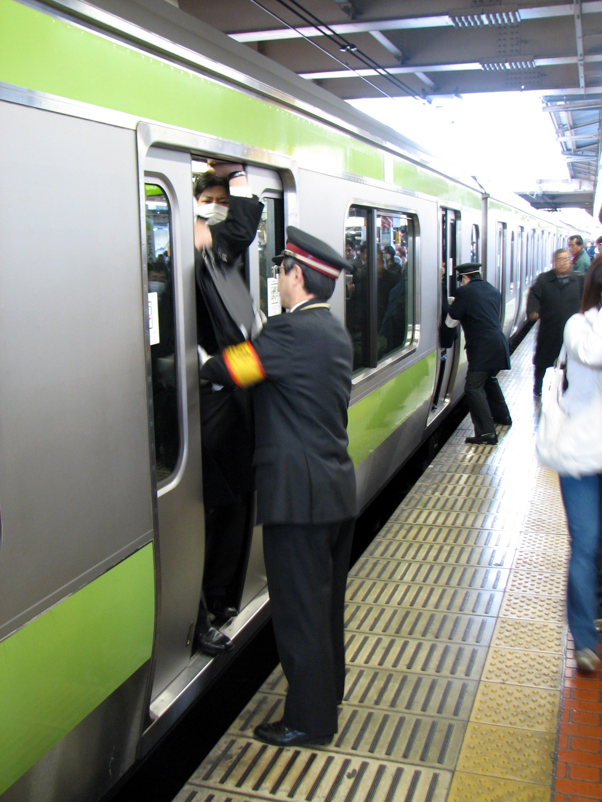 Attendants pushing people onto a train during rush hour at Ueno station, Yamanote line.