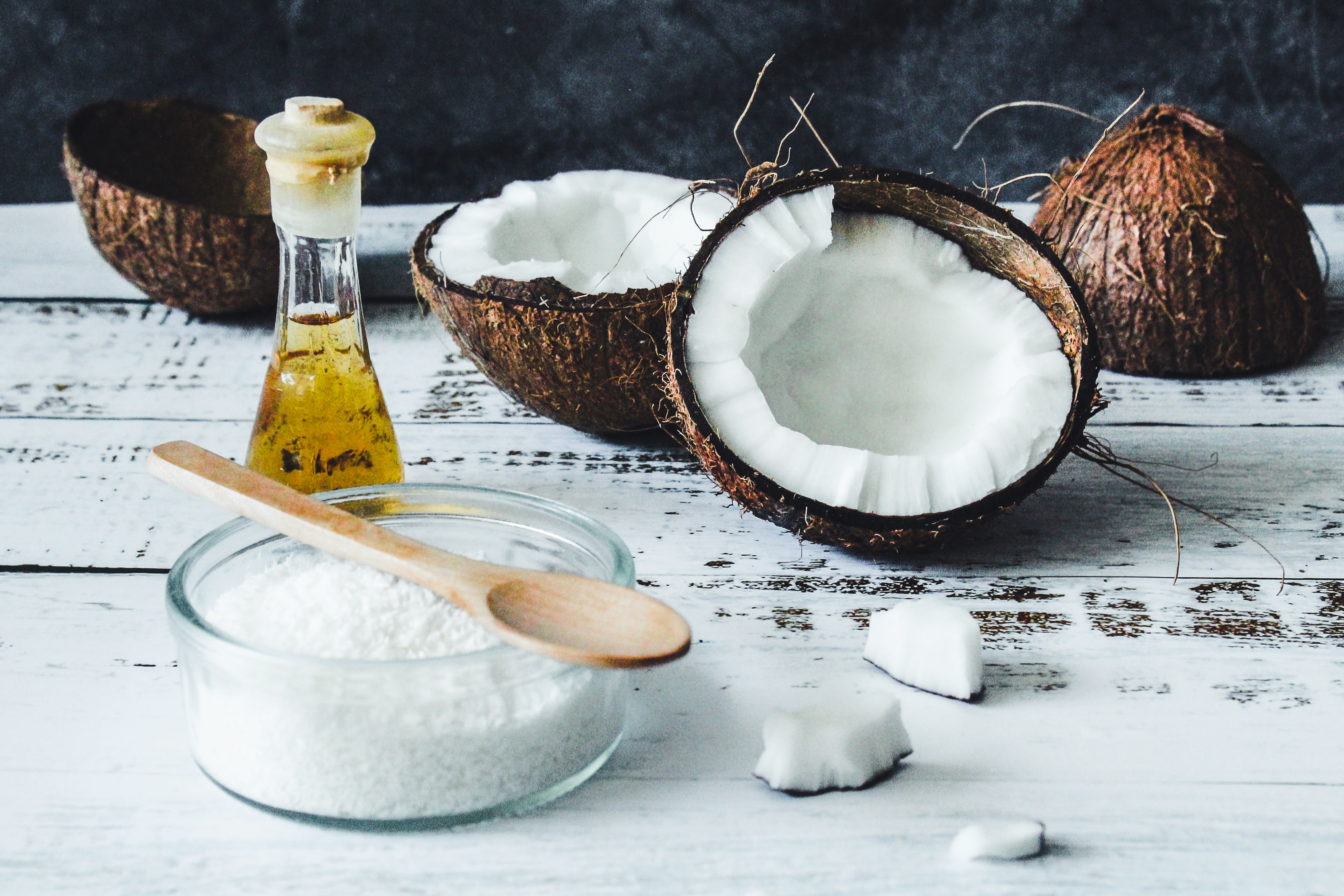 coconuts cut in half with liquid and solid coconut oil in bowls