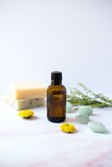 a bottle of essential oil surrounded by herbs and flavors