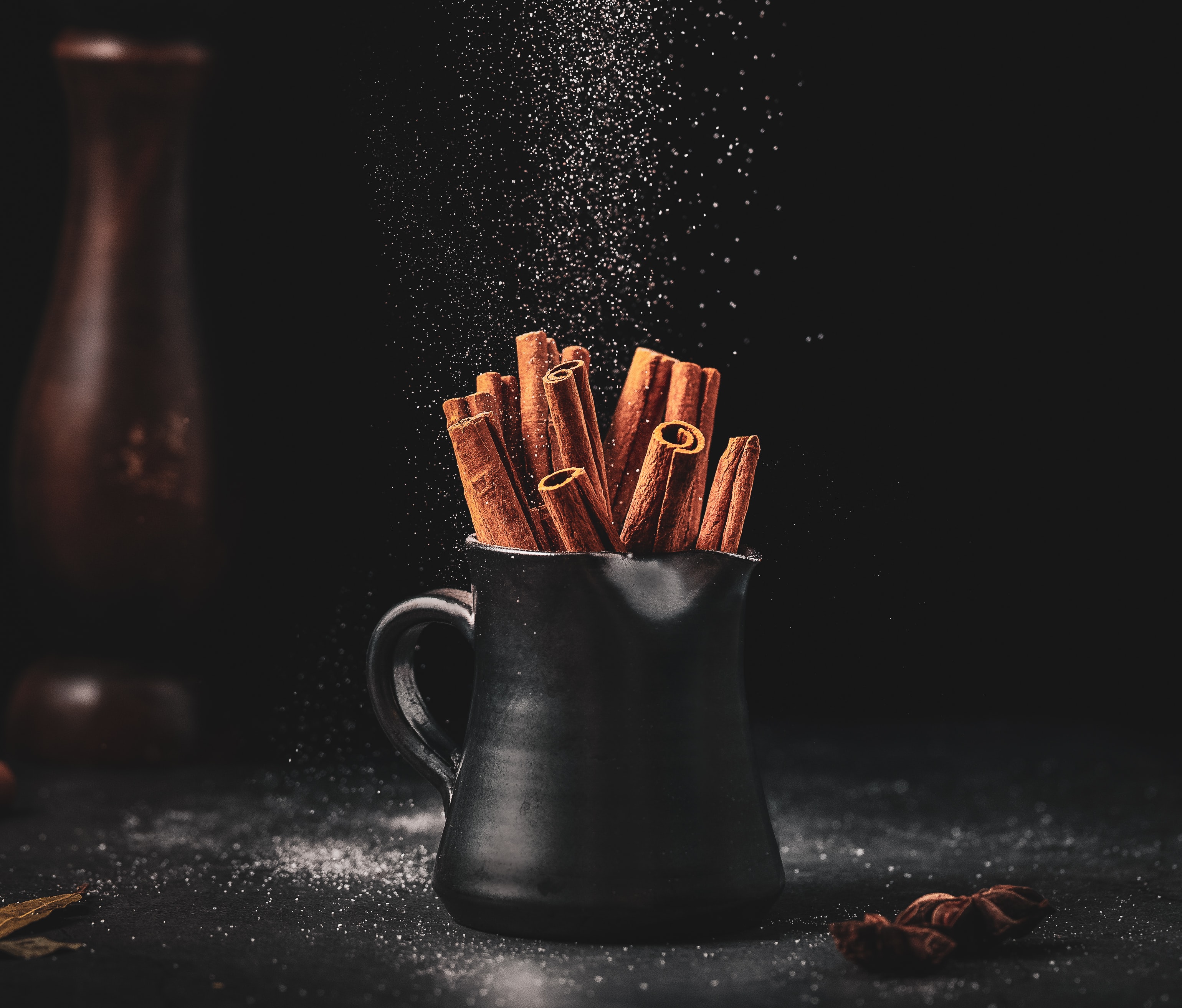 a black pitcher with cinnamon sticks in it