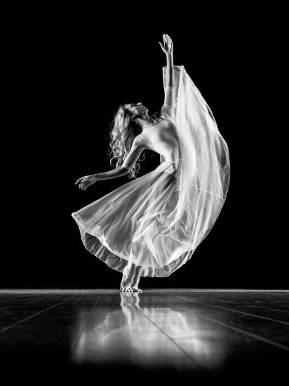 black and white picture of a woman dancing alone on a stage