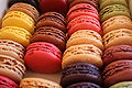 A variety of colored macarons including yellow, red, orange, green, blue, and brown.