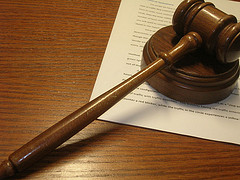 A gavel lying on a table with documents underneath it