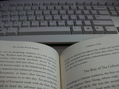 A book open in front of a keyboard.