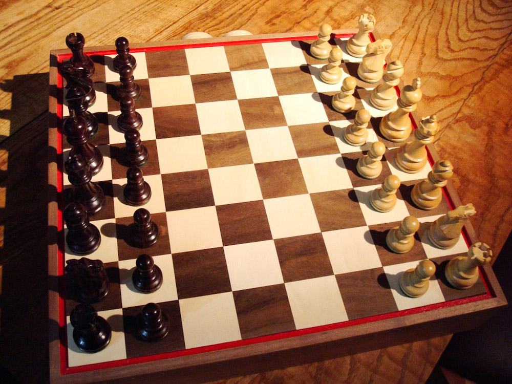 A chess set in black and white; a chess board with a full complement of thirty-two pieces; sixteen white and sixteen black pieces; a king and a queen, two bishops, two knights, two castles and eight pawns, each in black and in white.