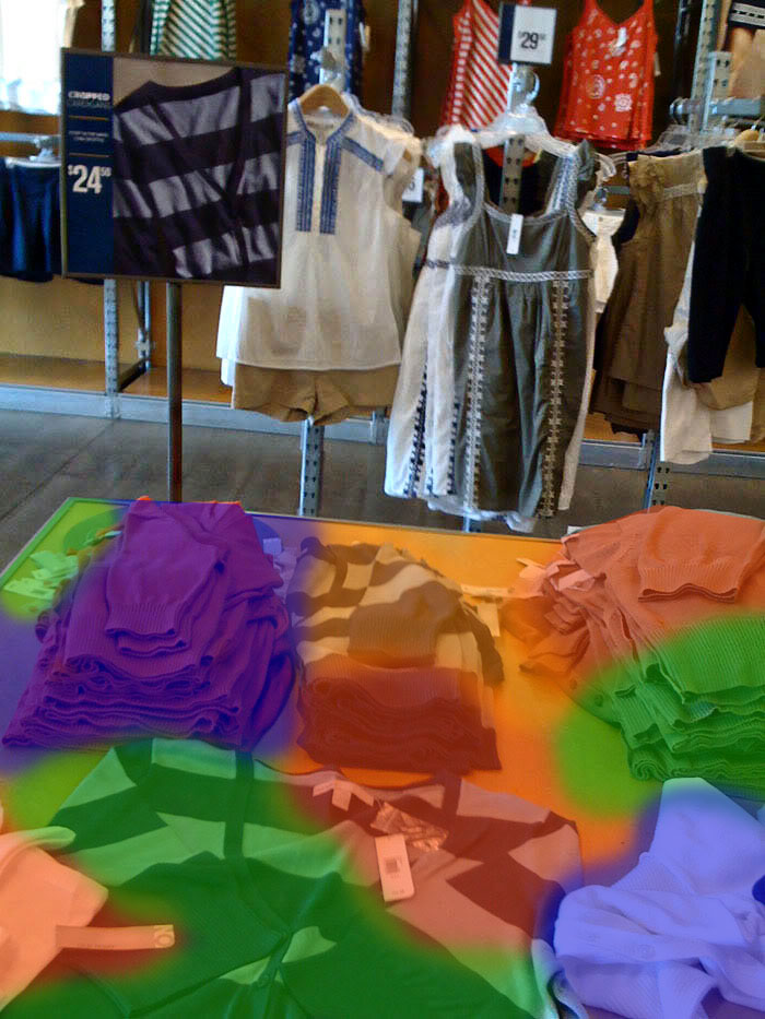 Overhead view of a clothing store. A table covered with merchandize is highlighted with a multicolored overlay that tints various items in red, green, orange, and blue.
