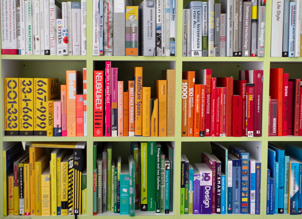 Books, arranged by color, on shelves.