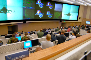 This image depicts a Fusion Center full of employees looking at control screens.