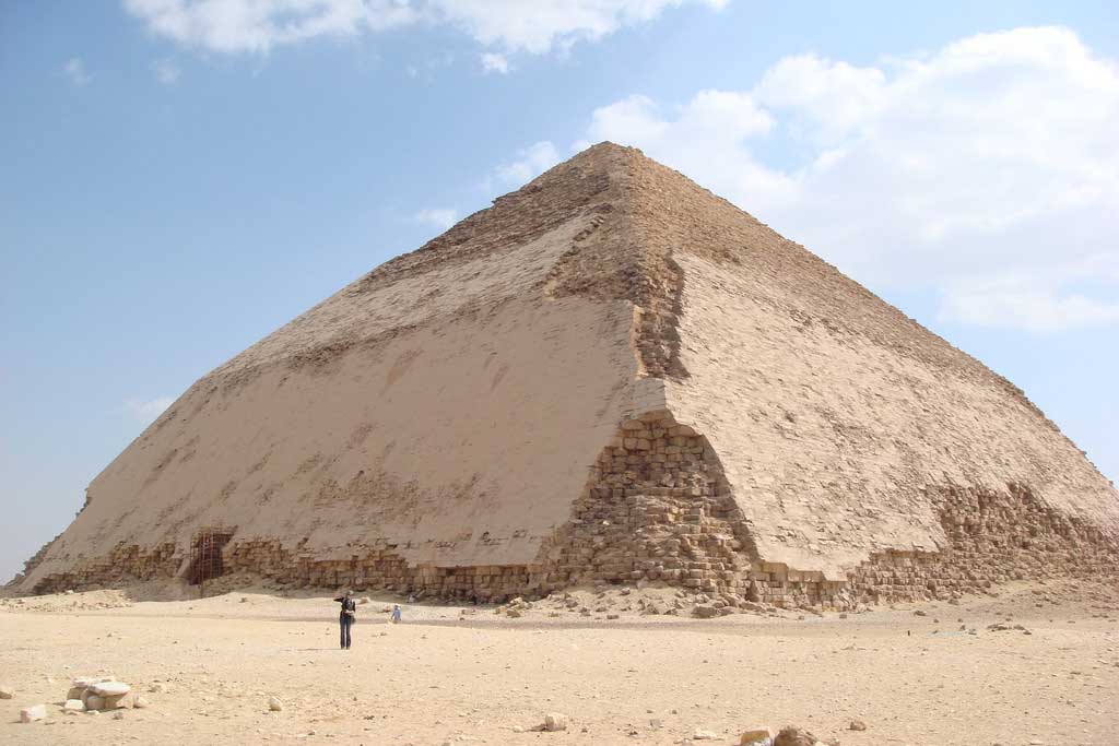 The picture is that of the Bent Pyramid. In this image, a smooth-sided pyramid has a large lower base and a disproportionately smaller triangular top.