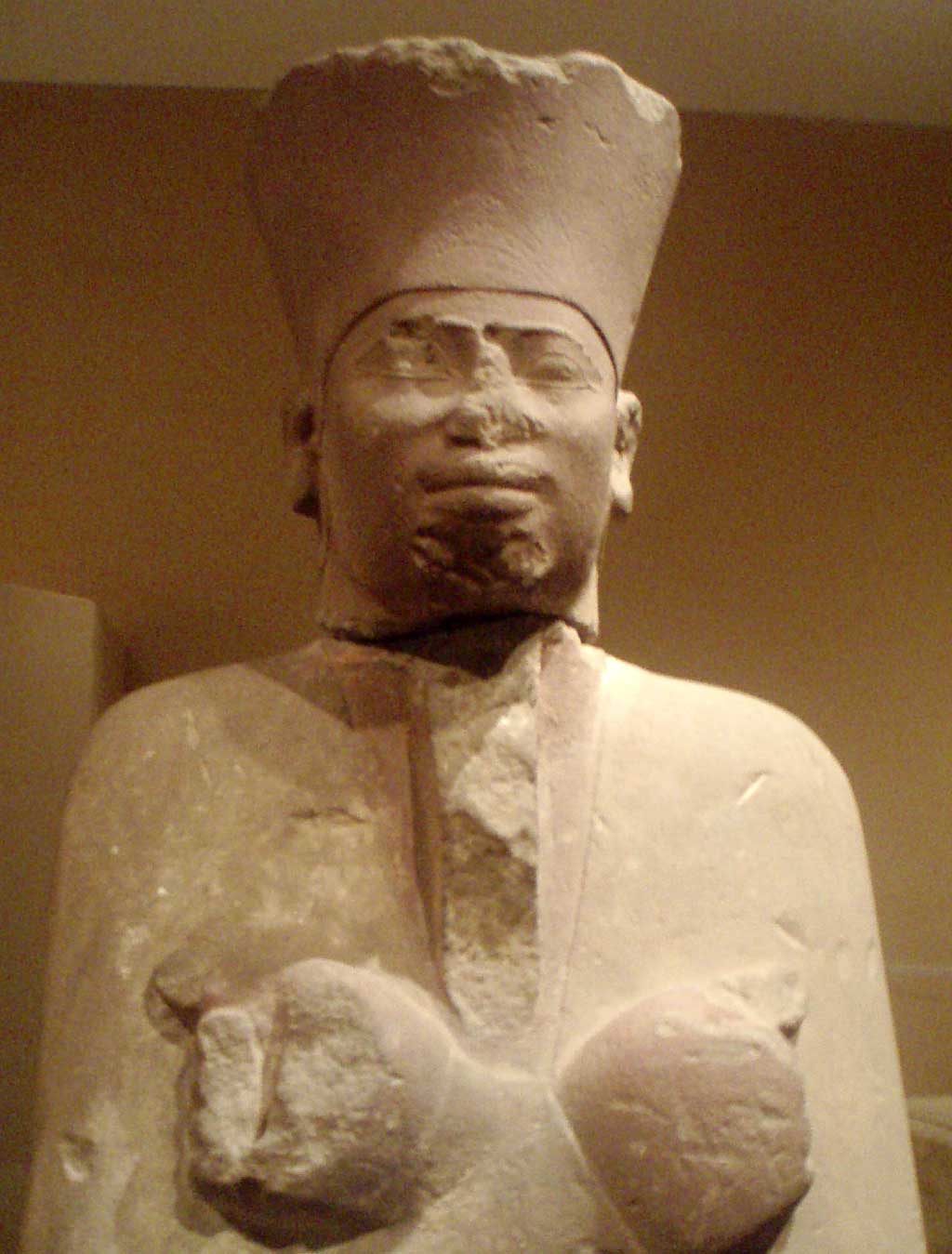 Image of a white sandstone statue of Mentuhotep II. Atop his head he wears the crown of lower Egypt.