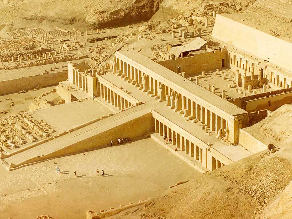 The picture is an aerial view of the massive temple of Hatshepsut. From overhead, there appears a long ramp leading up to a columned entrance way. An open courtyard where the temple precincts once presided.