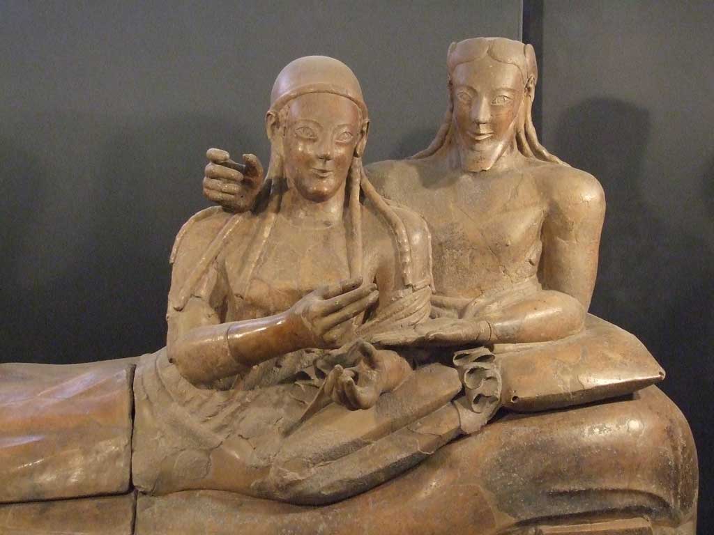Picture of husband and wife laying side by side atop the terra cotta sarcophagus.