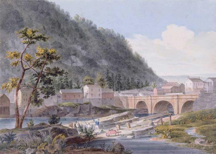 Bridge over the Erie Canal with buildings and a hill behind it