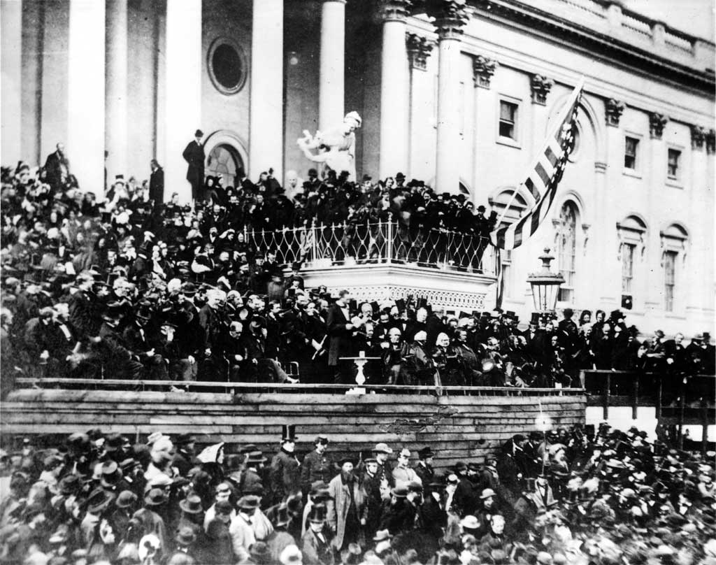 Abraham Lincoln giving his inaugural address on the east portico of the U.S. Capitol. A large crowd is gathered around.