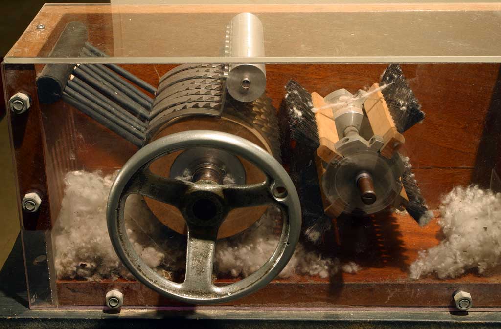A cotton gin on display at the Eli Whitney Museum showing the internal mechanisms and seeds being stripped from cotton.
