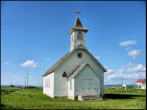 Photo of old white clapboard church building against blue sky