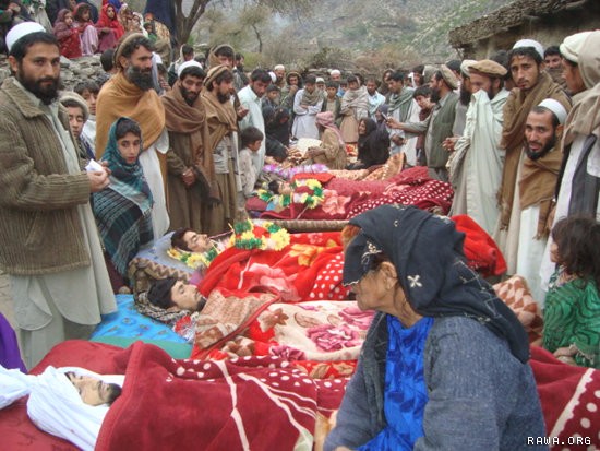 A large crowd gathers around the bodies of the victims.