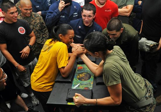 Two women arm wrestling while a crowd looks on