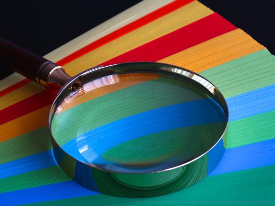 A magnifying glass lies over a sheet with stripes of different colors