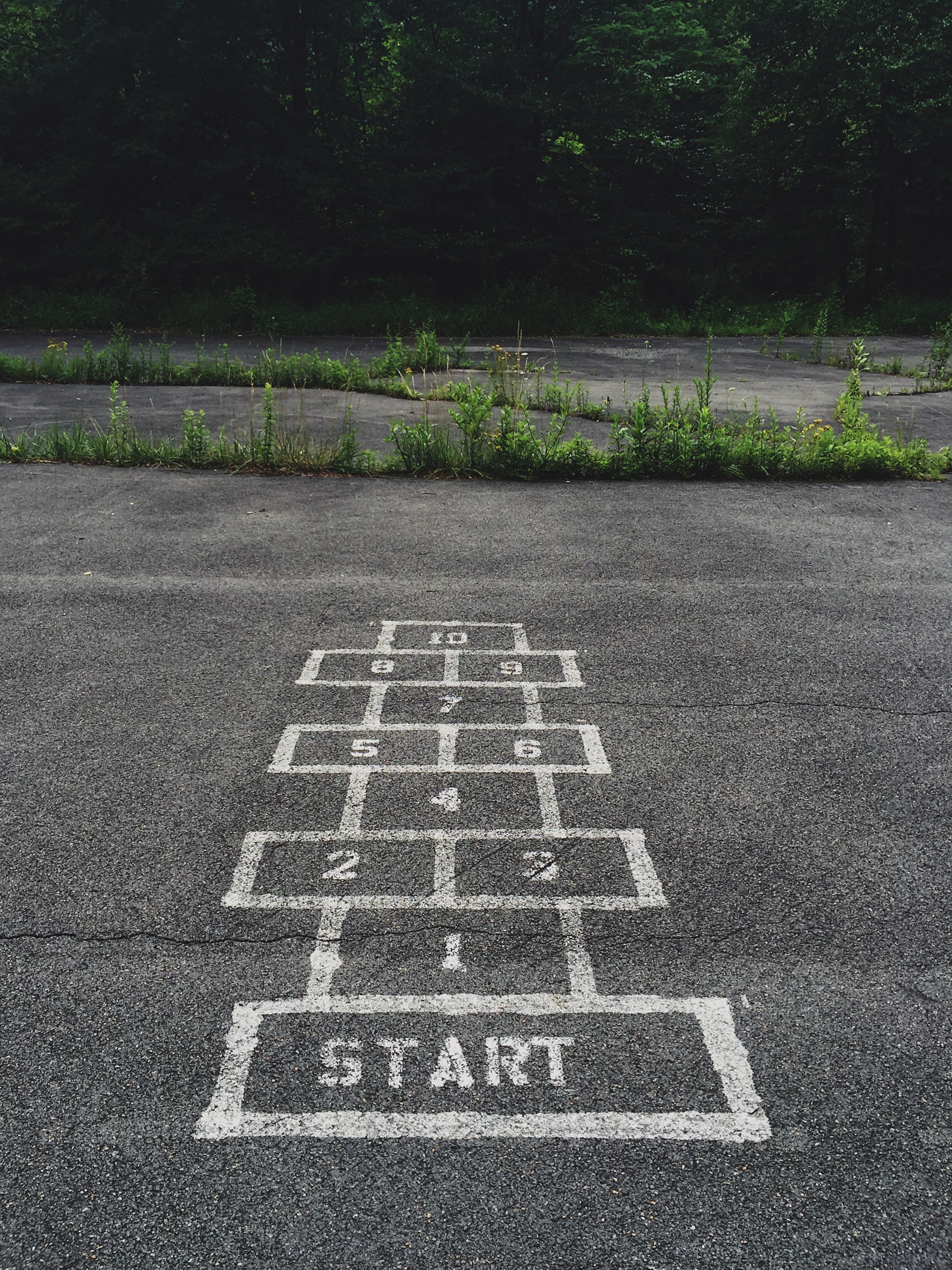 Une grille de marelle peinte sur de l'asphalte avec le mot « Start » peint sur le premier bloc.