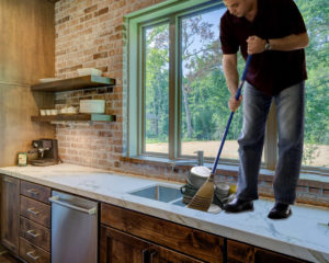 Photo of a man standing on a counter, sweeping the dishes