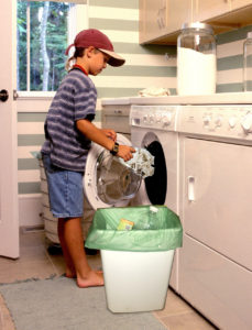 A boy putting trash in the washing machine