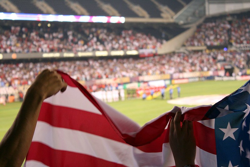 Hands holding a U.S. flag at a soccer game